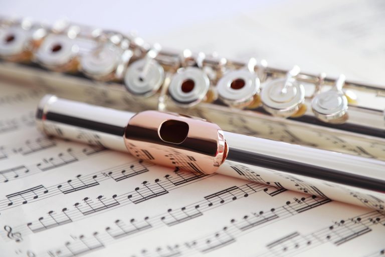 5 Best Flute Method Books for Intermediate-Advanced Flute Players - RentMyInstrument.com - Open-hole flute on sheet music