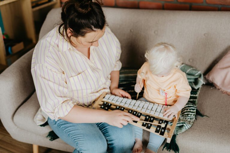 Baby playing music on the Xylophone with her mom